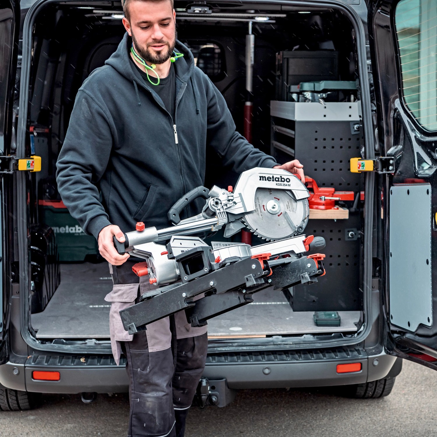 Mann trägt Metabo KGS 254 M Kapp- und Zugsäge aus einem Transporter. Inkl. 2 Sägeblätter.