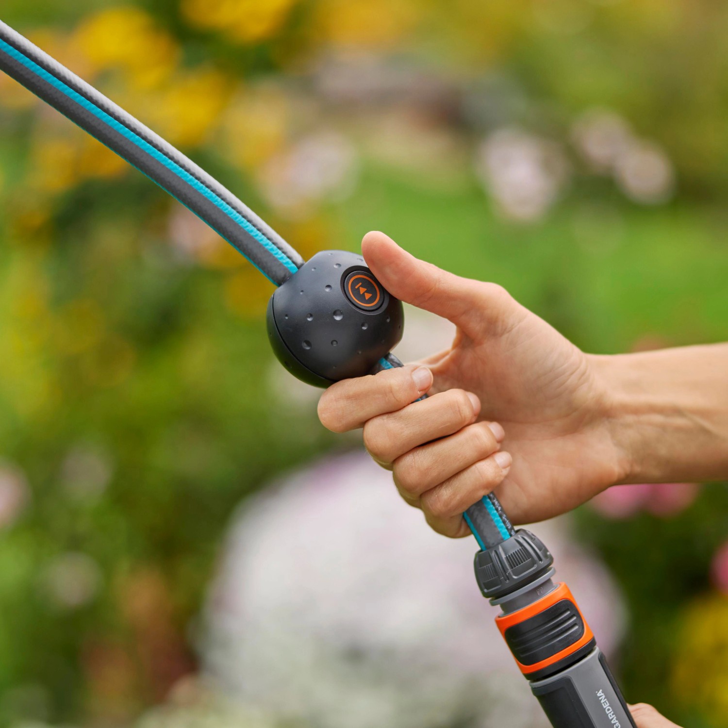 Hand betätigt Aufrollknopf am Gardena Akku-Schlauchwagen PowerRoll XXL mit 40m Gartenschlauch.