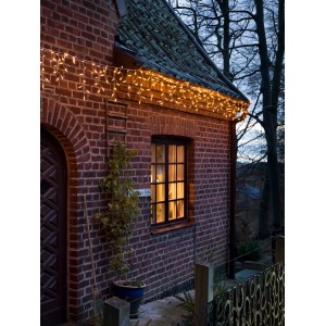 Konstsmide LED-Eisregen Lichtervorhang mit 200 bernsteinfarbenen LEDs am Backsteinhaus.
