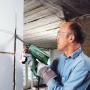Mann bohrt mit dem Bosch Bohrhammer PBH 2500 SRE ein Loch in die Wand.