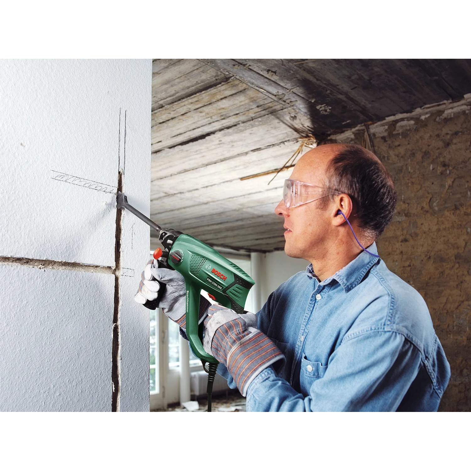 Mann bohrt mit dem Bosch Bohrhammer PBH 2500 SRE ein Loch in die Wand.