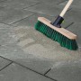 Außenaufnahme: Grauer Pflasterfugenmörtel wird mit Besen in Pflastersteine eingekehrt.