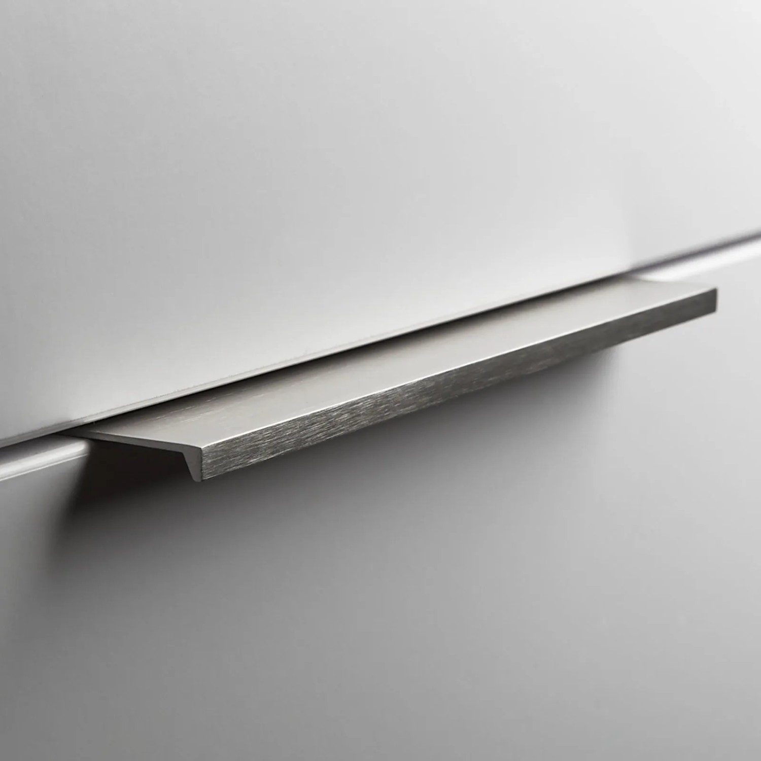 SOTECH Griffleiste Searl aus gebürstetem Aluminium in Edelstahloptik an heller Möbelfront.