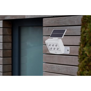 Weißer Briloner LED-Außenstrahler mit Solarpanel an einer Holzwand. Inklusive Bewegungssensor.