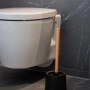 Wenko WC-Garnitur Basic Bambusa mit schwarzem Behälter und Bambus-Stiel vor einer Toilette.