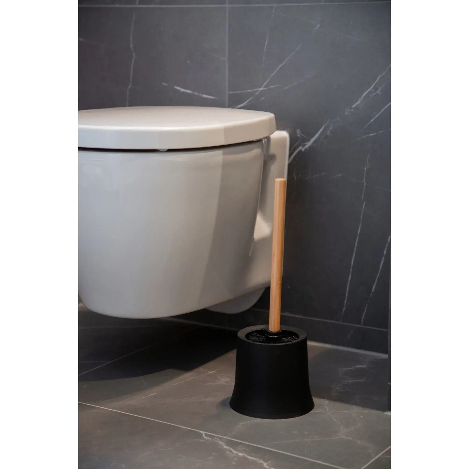 Wenko WC-Garnitur Basic Bambusa mit schwarzem Behälter und Bambus-Stiel vor einer Toilette.