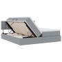 Hellgraues Stoffbett mit LED-Leisten und Stauraum unter der Matratze.