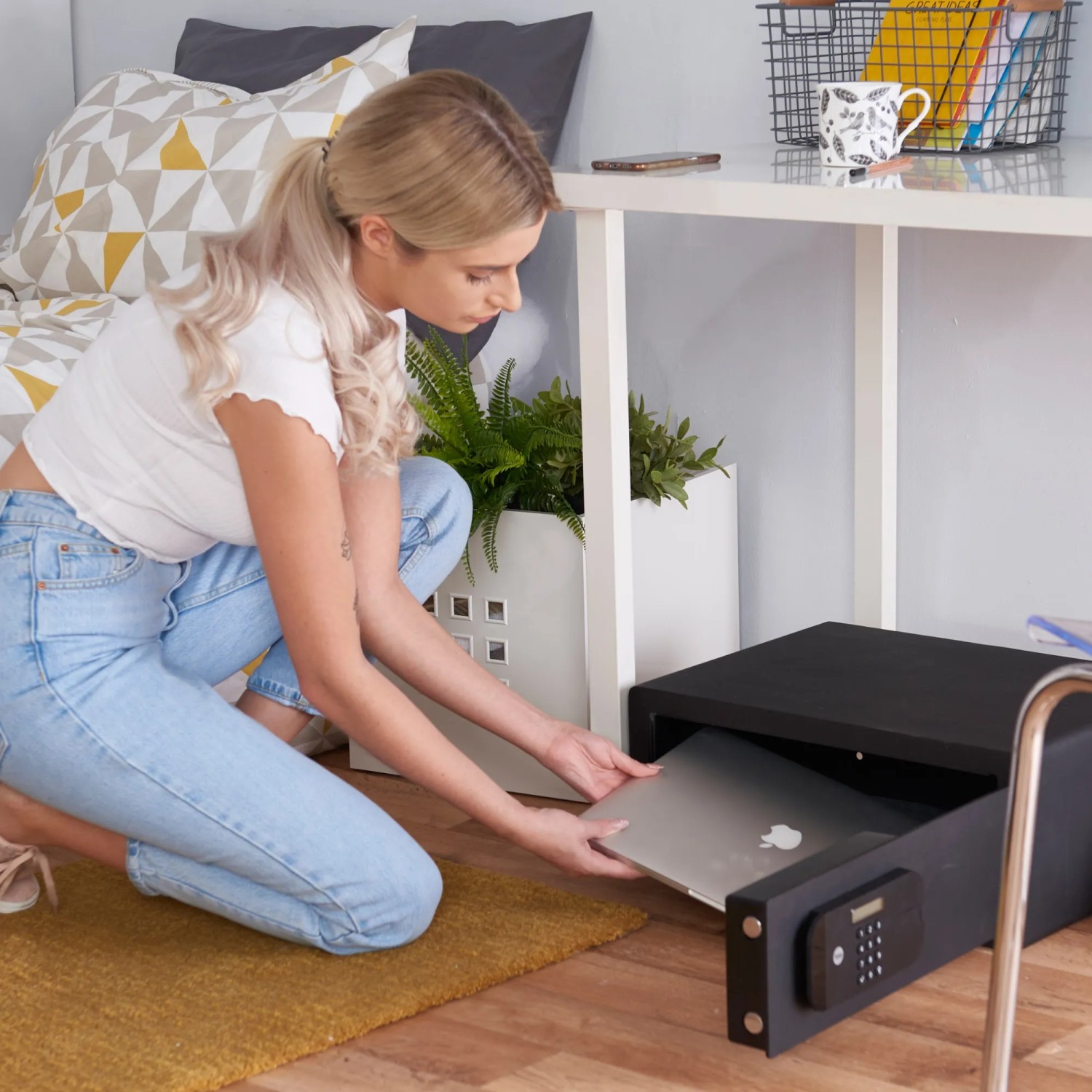 Frau legt Laptop in schwarzen Yale High Security Tresor mit Zahlencode.