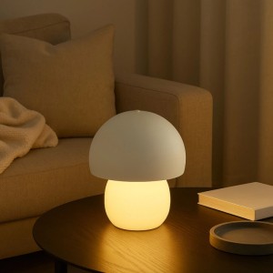 Weiße LED Tischleuchte Dupis im Pilzdesign auf dunklem Tisch, leuchtend. Kabellose, dimmbare Beleuchtung für gemütliche Räume.