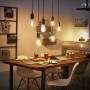 Philips Hue Filament Lampe E27 über Esstisch, warmweißes Licht im Retro-Look.
