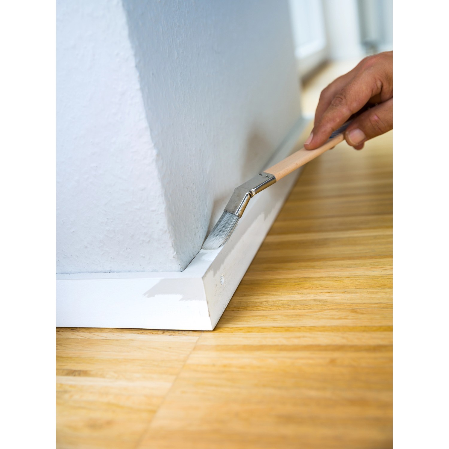 Anwendung: LUX Plattpinsel gebogen 20 mm beim Streichen einer Sockelleiste.