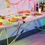 LUX Multifunktionstisch mit Aluminiumgestell, gedeckt mit Speisen und Getränken für eine Party.