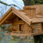 Braun gebeiztes Dobar Vogelhaus im Berghütten-Design mit Vogel am Futterplatz.