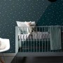 Dunkelblaue Vliestapete mit fluoreszierenden Sternen im Kinderzimmer. Zeigt den Glow-in-the-Dark Effekt.