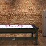 Reverso Spieltisch als Airhockey-Tisch mit roten Pucks vor Backsteinwand.