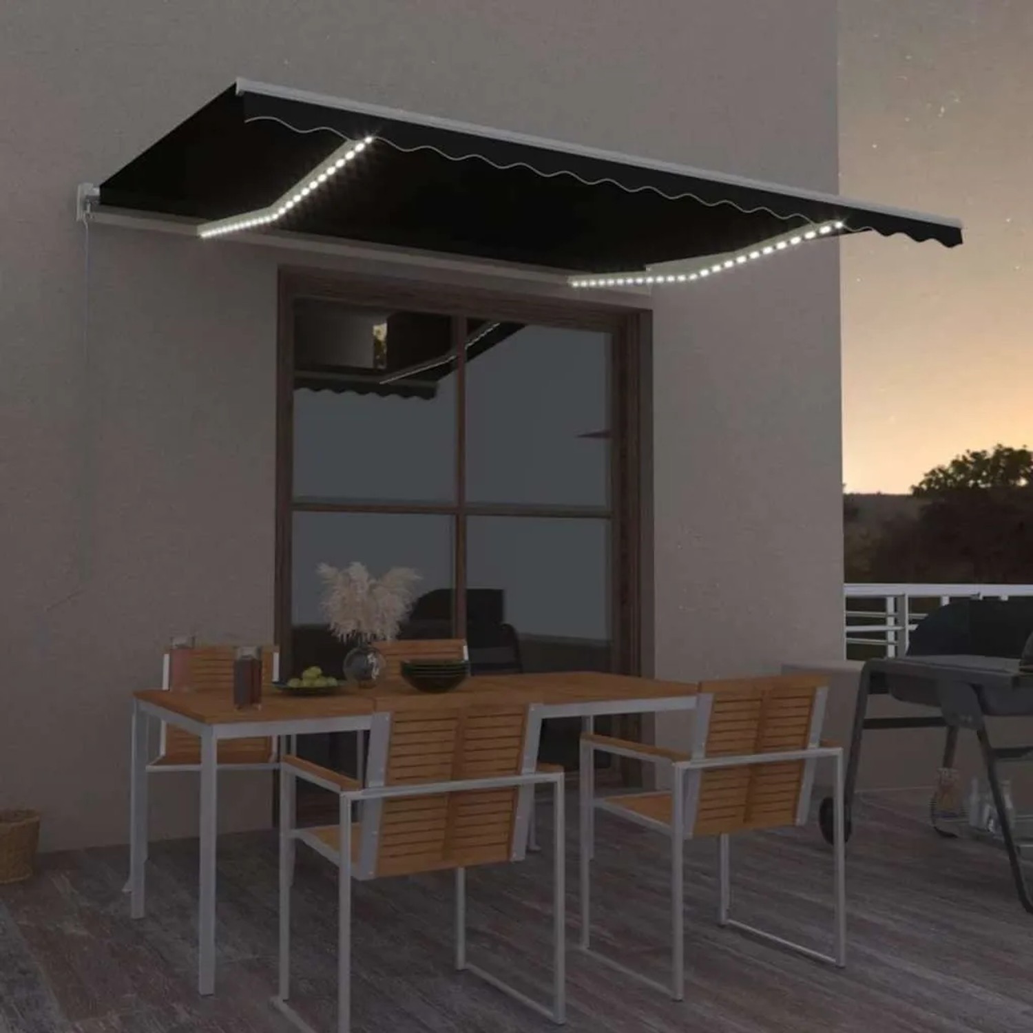 Anthrazitfarbene manuelle Markise mit weißem Rahmen und leuchtenden LEDs über einer Terrasse bei Nacht.