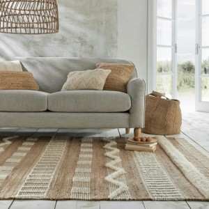 Flair Rugs Hochflorteppich Medina Jute Elfenbein mit strukturiertem Muster im Boho-Stil, im Wohnzimmer vor Sofa.