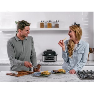 Ninja Foodi Grill und Heißluftfritteuse AG301EU in Grau-Schwarz mit Paar beim Essen in der Küche.