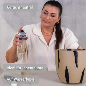 Frau sprüht mit belton Buntlack Cashmere Brown seidenmatt einen Blumentopf an.