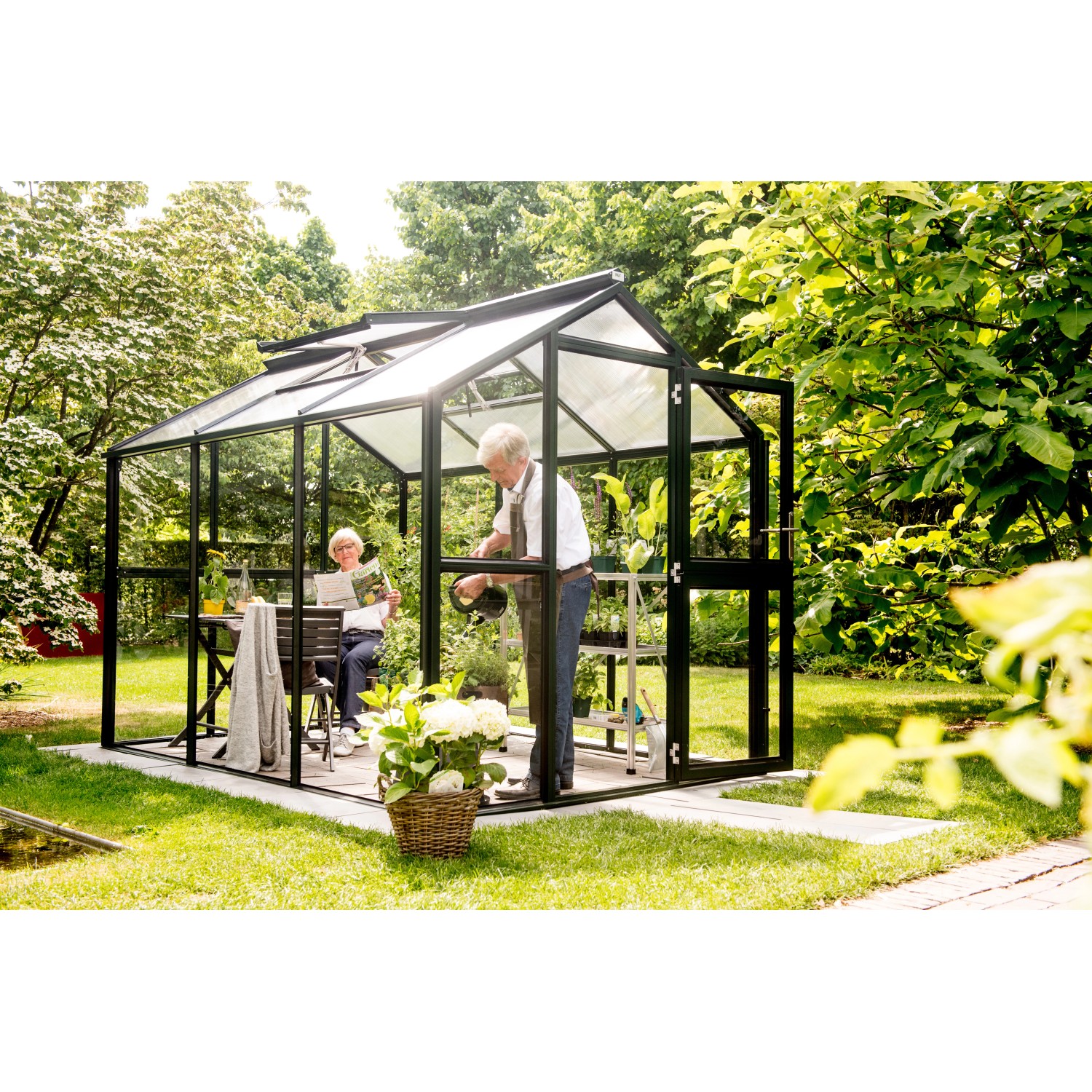 KGT Gewächshaus Galant III, tannengrün, 6,65 m² mit Personen bei der Gartenarbeit.