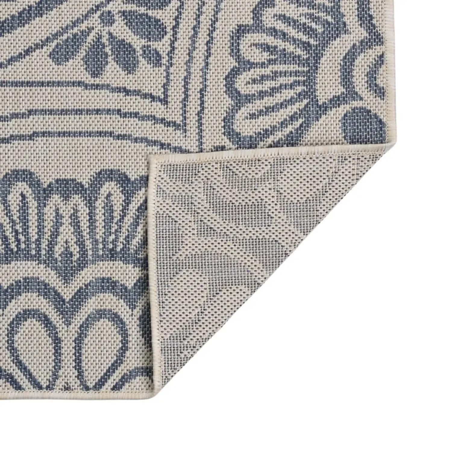 Blauer Outdoor-Teppich mit floralem Flachgewebe-Muster. Eine Ecke ist umgeschlagen und zeigt die strukturierte Unterseite.