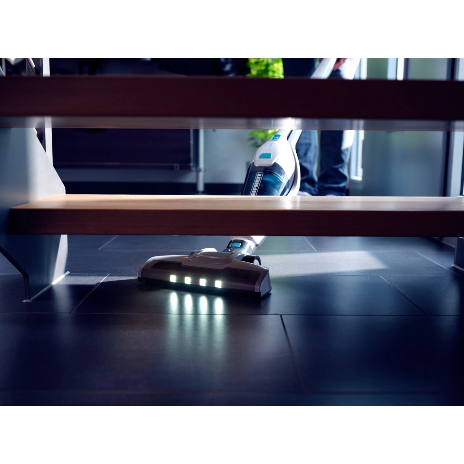 Leifheit Akku-Staubsauger Rotaro im Einsatz unter Treppe mit LED-Beleuchtung.