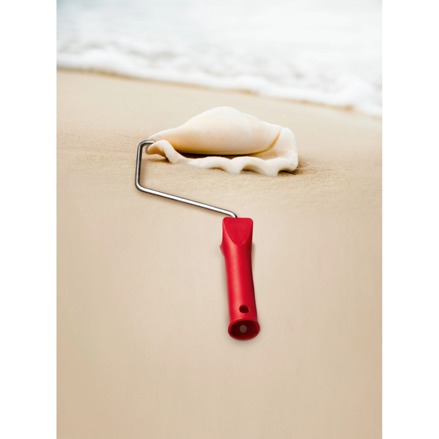 Farbe „Sand“ mit Farbroller auf Sandstrand und Muschel. Schöner Wohnen Trendfarbe.