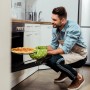 Mann holt knusprige Pizza auf rundem, antihaftbeschichtetem Pizzablech aus dem Ofen. Perfekt für das Pizzablech Set.