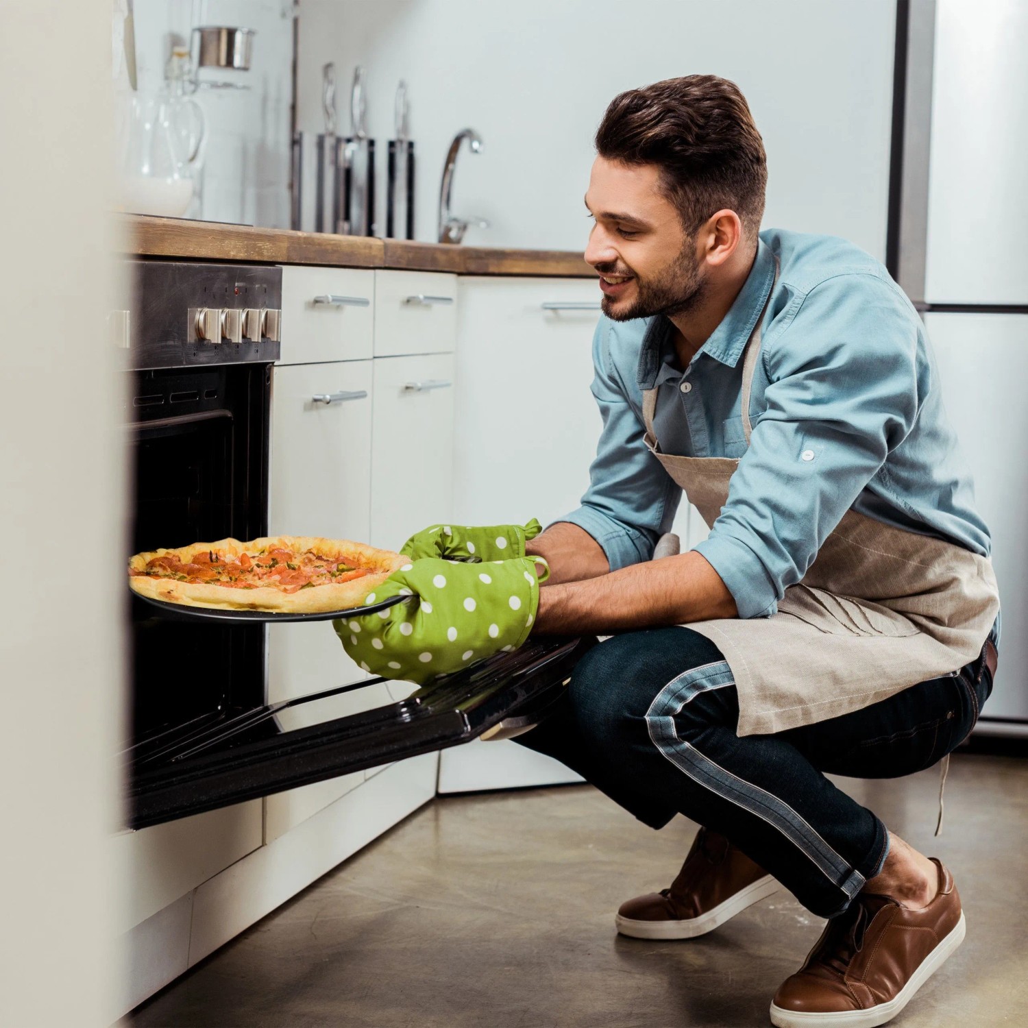 Mann holt knusprige Pizza auf rundem, antihaftbeschichtetem Pizzablech aus dem Ofen. Perfekt für das Pizzablech Set.