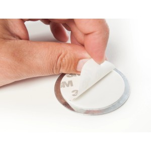 Magnetpad für Rauchmelder (Ø 7 cm): Hand zieht Schutzfolie ab, Montage ohne Bohren.