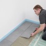 Mann verlegt Fliesen auf Perobe Elektro-Fußbodenheizung (2 m²) im Raum.