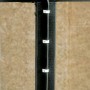 Schwarzes Kabel befestigt mit weißen Nagelschellen (7-11mm) an einer dunklen Holzkonstruktion.