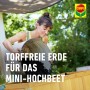 Frau befüllt Mini-Hochbeet mit torffreier Compo BIO Erde aus Eimer. Ideal für ökologisches Gärtnern.