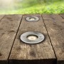 Zwei runde, silberne Bodeneinbaustrahler Style II GU10 40W auf einer Holzterrasse.