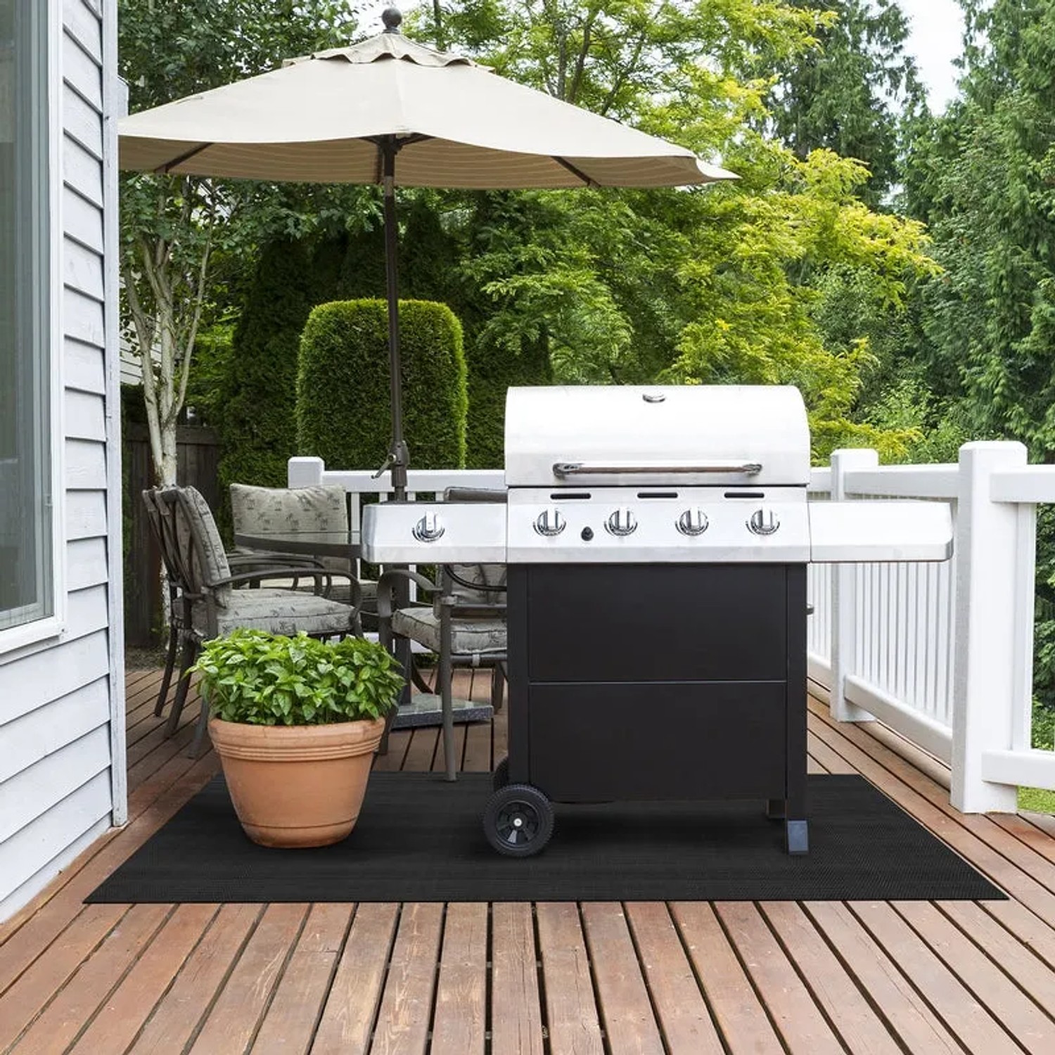 Schwarzer KARAT Outdoor Teppich Lucca unter Grill auf Holzterrasse.