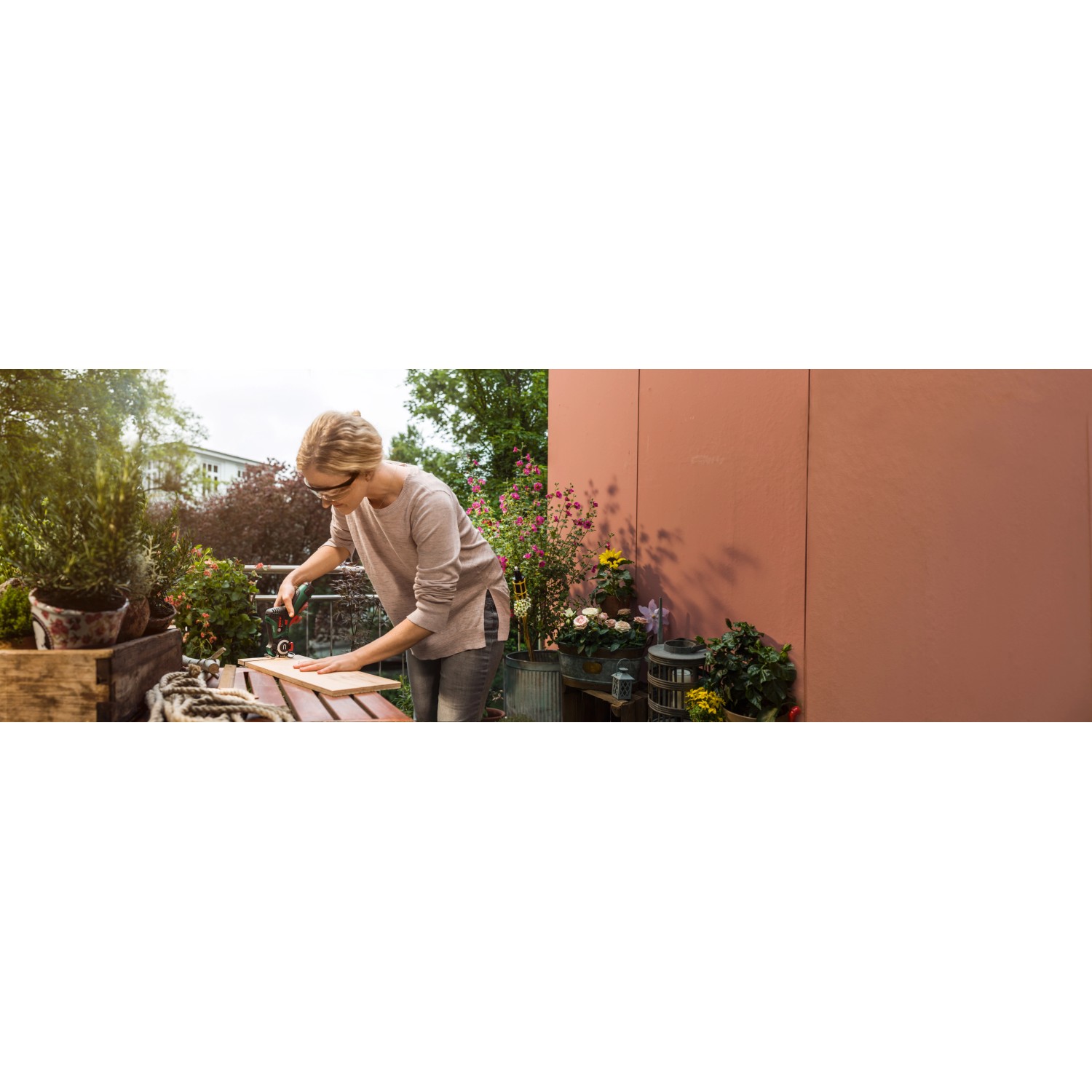 Frau sägt Holz mit Bosch EasyCut 12 Akku-Säge (12V) mit NanoBlade-Technologie auf Balkon.