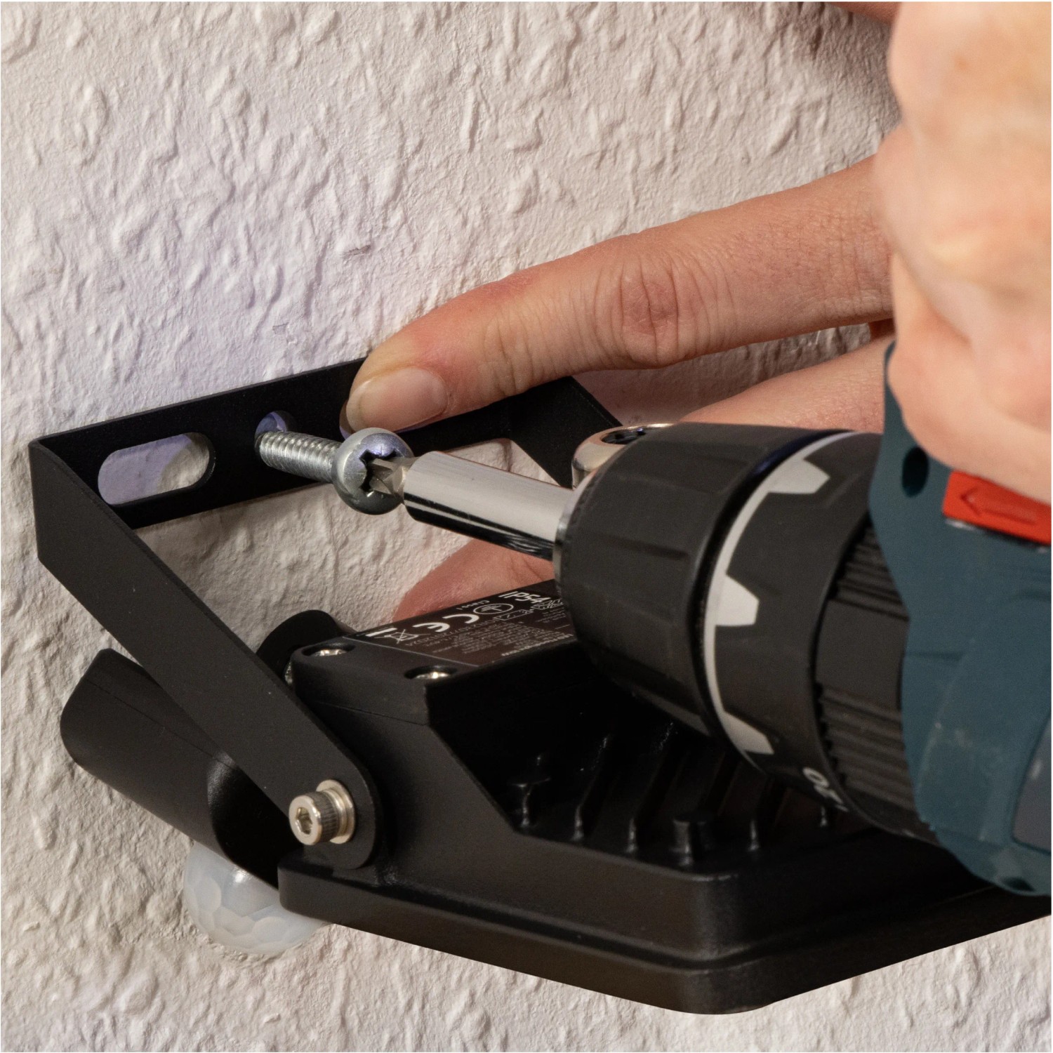 Montage eines schwarzen LED's Work Außenstrahlers mit Sensor an einer Wand.
