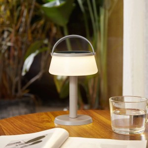 Lindby LED-Tischleuchte Mikkel in Creme, dimmbar, spritzwassergeschützt, mit Griff auf Holztisch.