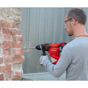Mann bohrt mit rotem Einhell Bohrhammer TC-RH 900 in eine Ziegelwand.
