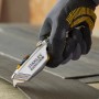 Stanley FatMax 2in1 Messer schneidet Laminat, Hand mit Schutzhandschuh.