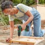 Frau nutzt Bosch EasyDrill 18V-40 Akkubohrschrauber für Holzprojekt im Garten. Vielseitiger Akkuschrauber.