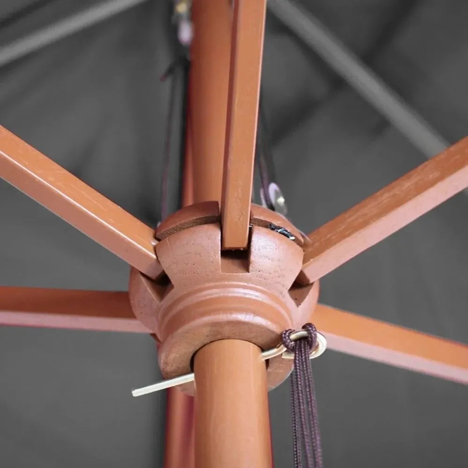 Sonnenschirm: Detail des braunen Holzgestells mit Seilzugmechanismus und anthrazitfarbenem Stoff.
