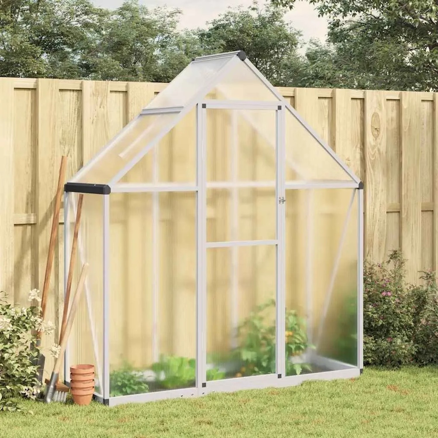 Silbernes Aluminium-Gewächshaus mit transparenten Polycarbonatplatten im Garten. Ideal für Pflanzenzucht.