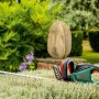 Bosch UniversalHedgeCut 60 Elektro-Heckenschere im Garten, grüne Hecke im Hintergrund.