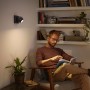 Philips Hue Buckram Spot, schwarz, mit Mann beim Lesen im Sessel. Warmweißes Licht.