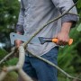 Fiskars WoodXpert XA3 Machete in Aktion: Mann schneidet Ast mit der Gartensäge.