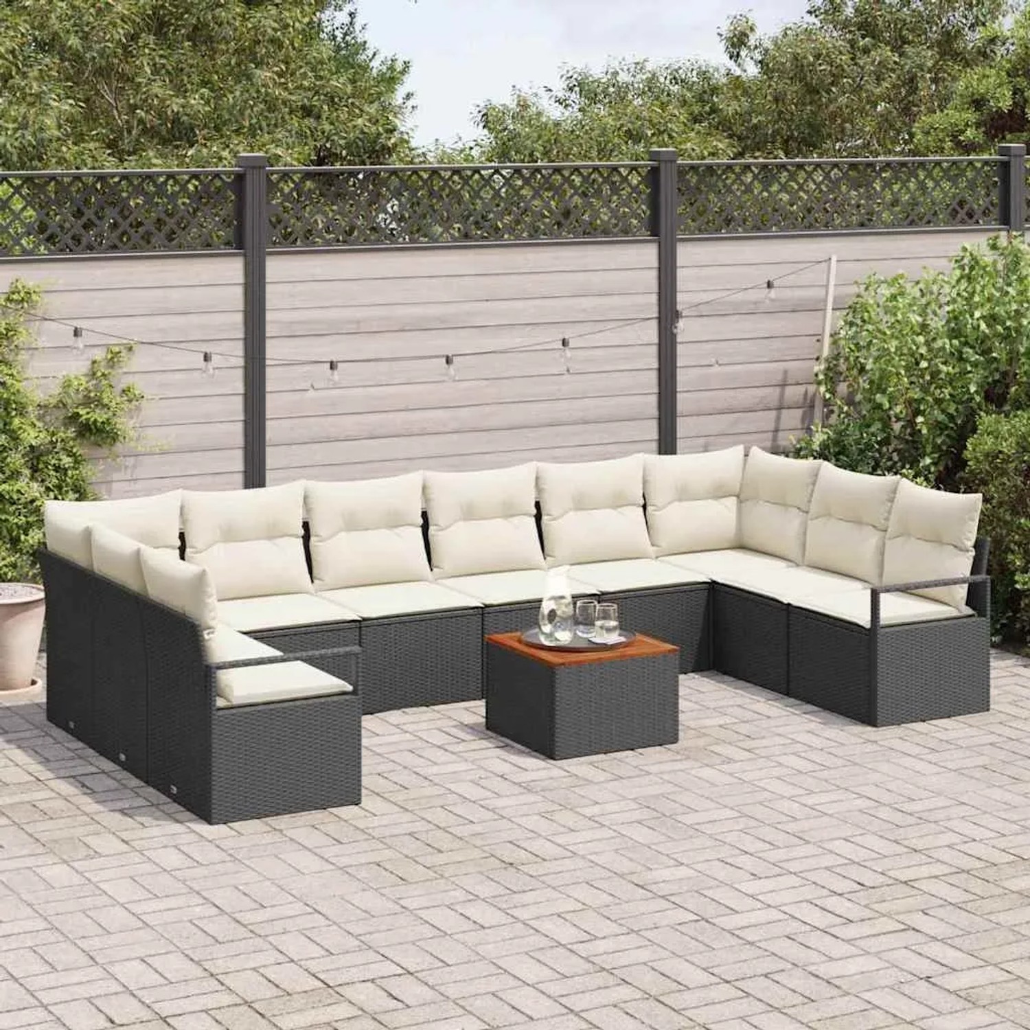 Schwarzes 11-teiliges Garten-Sofa-Set aus Poly Rattan mit Tisch und hellen Kissen.