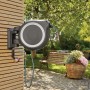 Gardena Wand-Schlauchbox Roll Up L mit 30m Schlauch an Hauswand mit Gartenszene im Hintergrund.