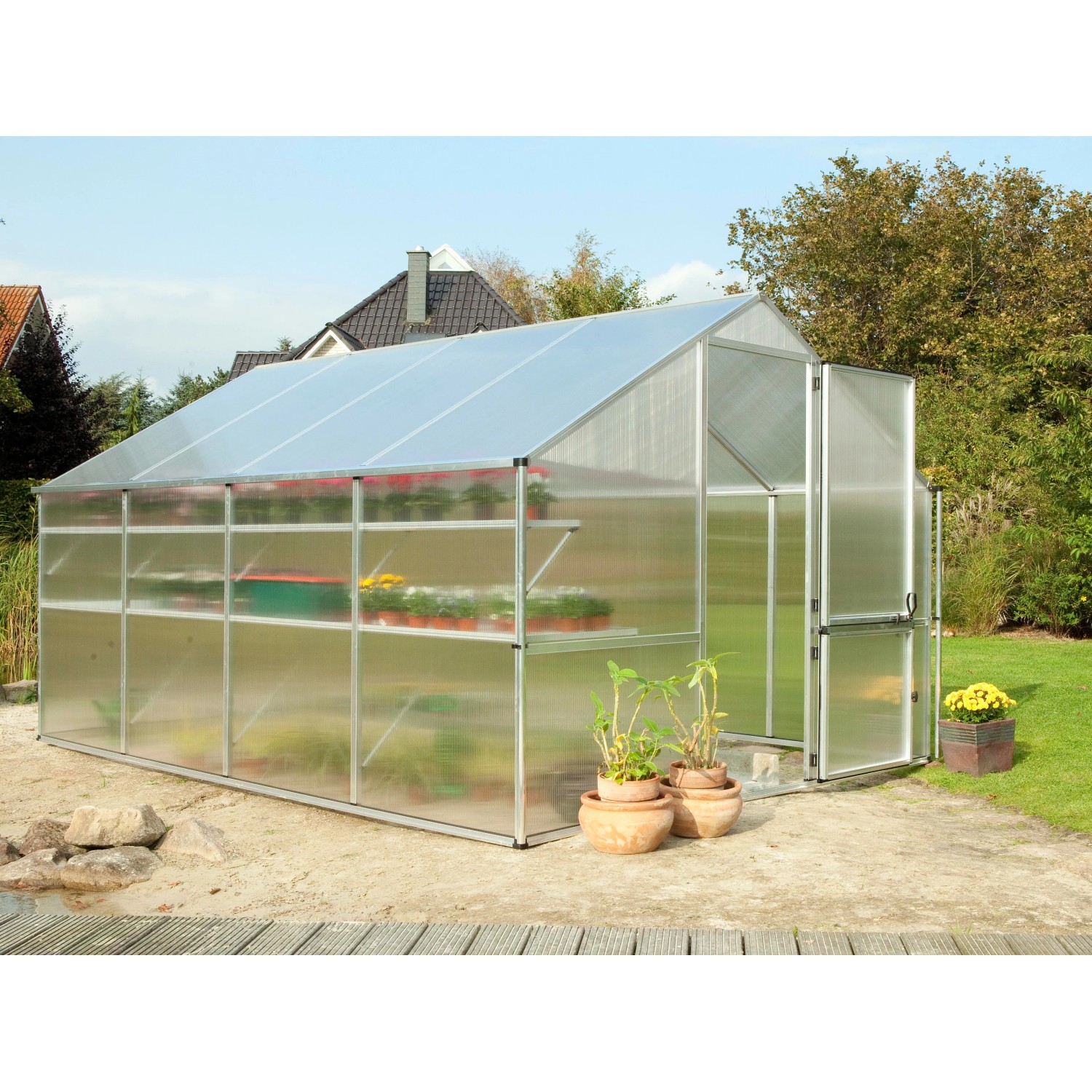 KGT Gewächshaus Orchidee Alu blank, 12,74 m², mit Pflanzen und Regalen im Garten.