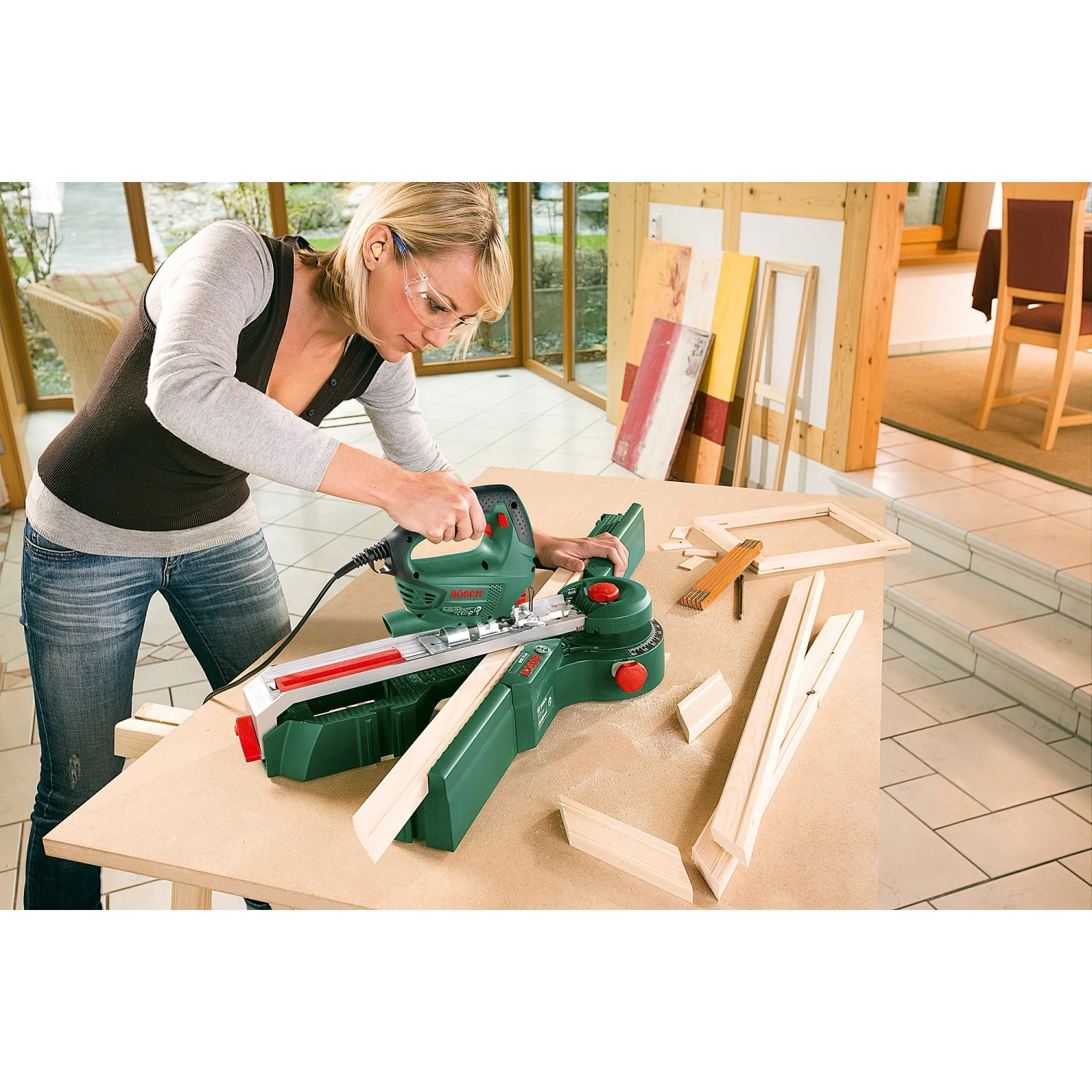Frau sägt Holz mit Bosch Stichsäge PST 700 E. Kompakte 500W Säge für präzise Schnitte.